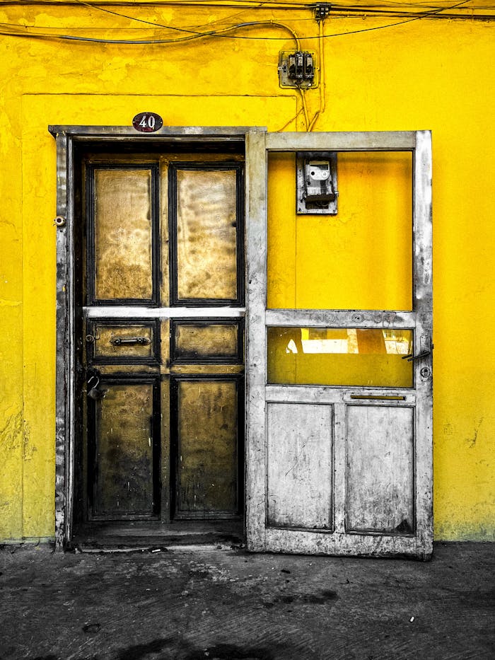 A rustic wooden door on a vibrant yellow wall, featuring a padlock and minimal decor.