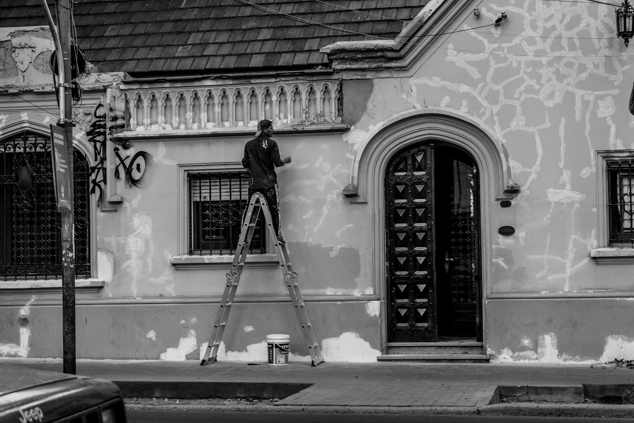 Black and white photo of a man painting a historic building in Mendoza, Argentina.