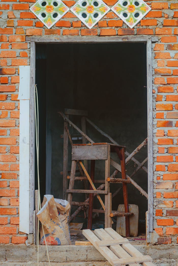 A view into an unfinished building with exposed brick walls and construction tools.
